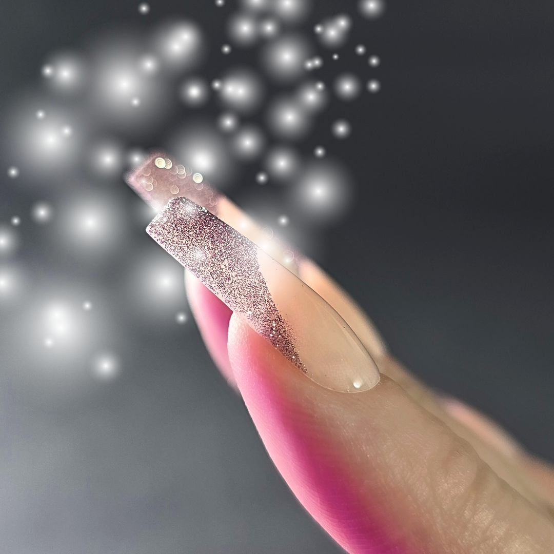 A close-up of a hand wearing elegant press-on nails with a shimmering design, featuring a soft glowing effect in the background for a glamorous look.