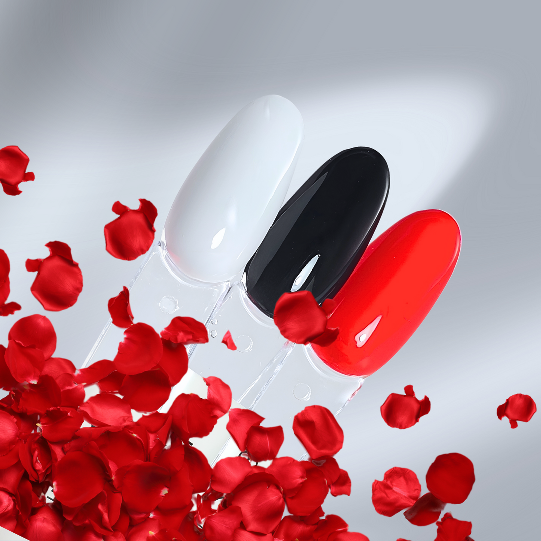 Elegant nail tips in glossy white, black, and red shades, surrounded by floating red petals. A stylish and bold gel polish look.