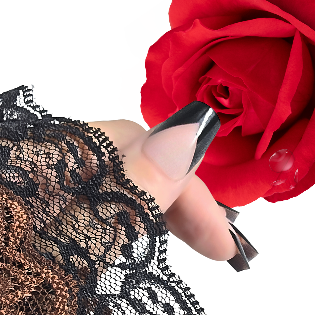 A close-up of a thumb wearing a White Diamond Nails press-on nail in French Chic, shade 112. The design features a nude base with a bold black French tip, showcasing a sleek and modern look, set against a clean background.