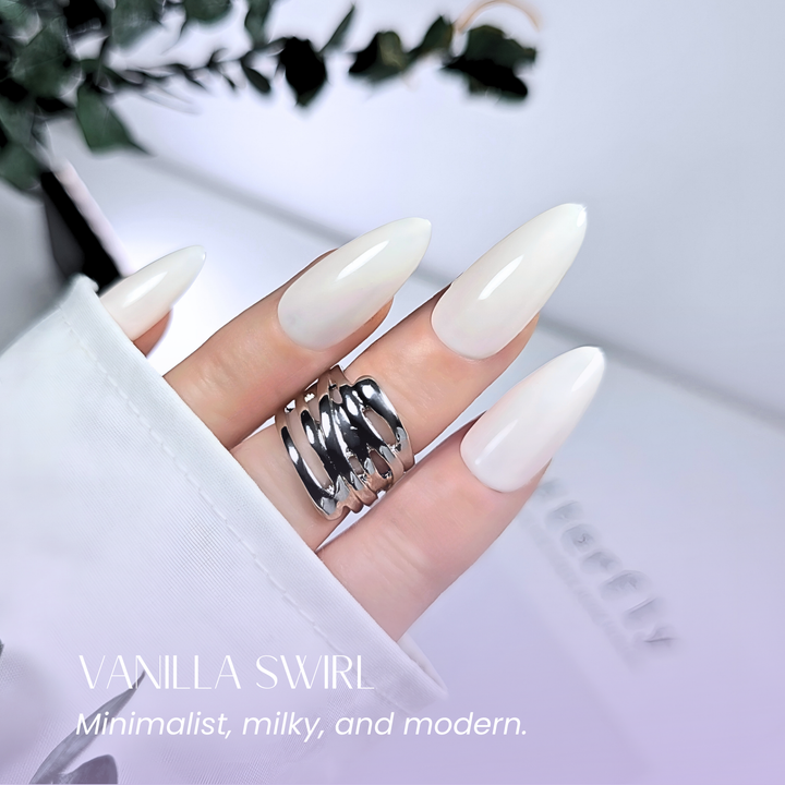 Natural neutral manicure with soft white gel and silver rings.