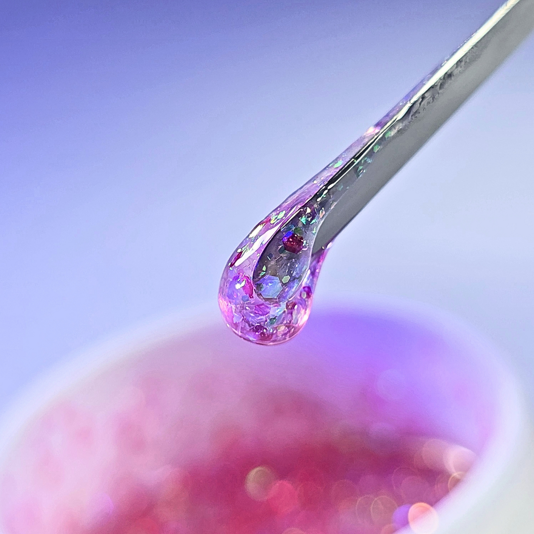 A close-up of a nail brush lifting a glitter-infused hard gel from a jar, showcasing its rich texture and shimmer. Perfect for strong, elegant nail enhancements.