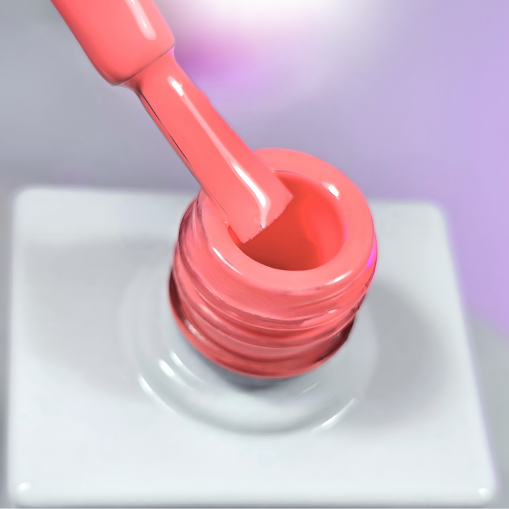 A bold coral gel polish being pulled from the bottle with a brush, revealing its rich pigmentation and glossy, full-coverage texture. The background has a subtle purple gradient, emphasizing the polish’s energetic and fresh appeal.