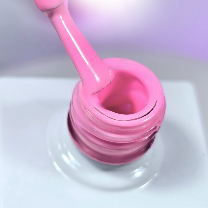 A close-up of a vibrant pink gel polish being lifted from the bottle with a brush, showcasing its creamy, highly pigmented formula. The background has soft purple lighting, enhancing the luxurious texture of the gel.