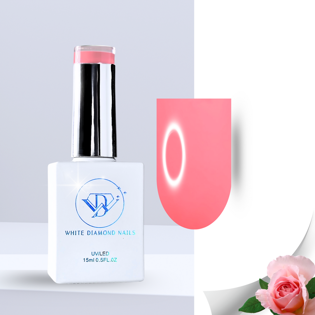 A bold and vibrant rosy coral gel polish swatch with a glossy, high-pigment finish, showcased on a clear nail tip. Surrounded by wet green leaves, delicate pink petals, and smooth white pebbles, this shade captures the confidence and allure of wild roses.